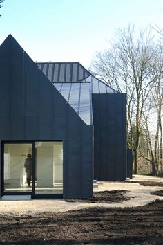 a person standing in the doorway of a building with black shingles on it's roof