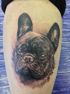 a black and white tattoo of a dog's head on the leg, with blue eyes