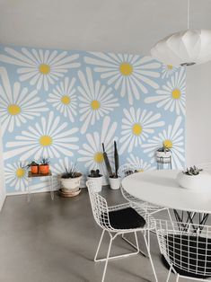 a white table and chairs in front of a blue wall with yellow flowers on it