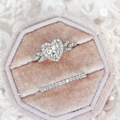 two engagement rings sitting on top of a velvet case