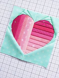 a heart shaped patchwork piece on top of a quilting mat with scissors and thread