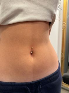 a woman's stomach with a tiny gold ball on the middle of her belly