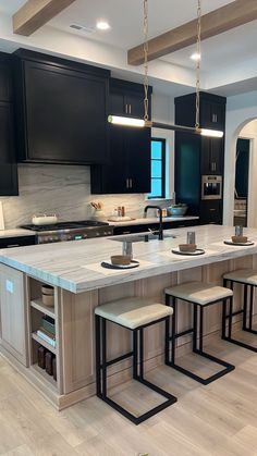 a large kitchen with black cabinets and white counter tops is pictured in this image, there are four stools at the center of the island