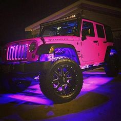 a pink jeep is parked in front of a house with purple lights on the side