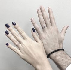 two hands with black and white nail polish holding each other's hand up in the air