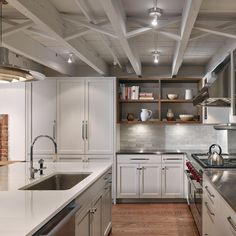 a large kitchen with white cabinets and stainless steel appliances, along with wood flooring