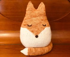 a knitted fox sitting on top of a wooden bench