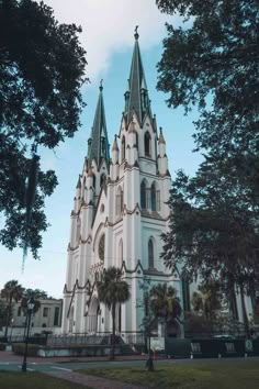 a large white church with green steeples surrounded by trees