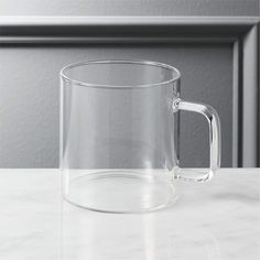 a clear glass mug sitting on top of a white countertop next to a gray wall