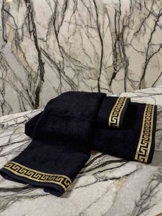 two black towels sitting on top of a marble counter covered in gold trimmings