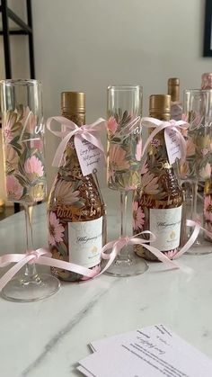 there are many bottles and glasses on the table with pink ribbons tied around each bottle