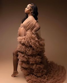 a woman in a long dress sitting on top of a pile of ruffled material