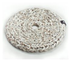 a close up of a knitted object on a white surface with a black button