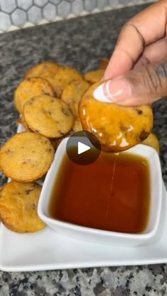 a person dipping something into a bowl of sauce on top of crackers and cookies