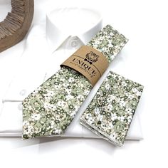 a tie and pocket square sitting on top of a white table next to a wooden object