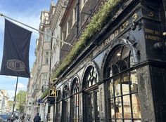 an old building with many windows and plants growing on the side of it's front