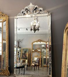 a large mirror sitting on top of a table next to two chairs and a chandelier