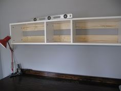 a wall mounted shelf with two speakers and a red light on the floor next to it