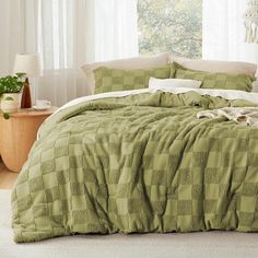 a bed with green comforter and pillows in a room