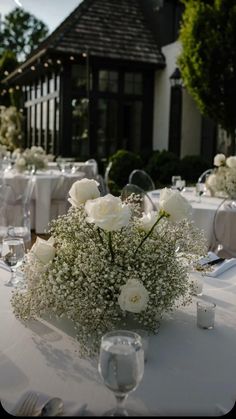 the table is set with white flowers and baby's breath in centerpieces