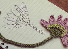 a crocheted flower sitting on top of an open notebook