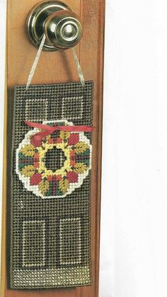 a door hanger with a cross - stitch design on it, hanging from a wall