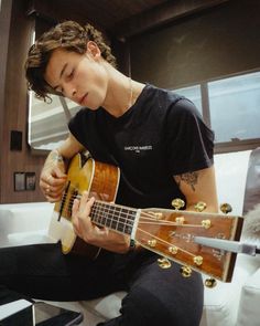 a young man playing an acoustic guitar in his living room