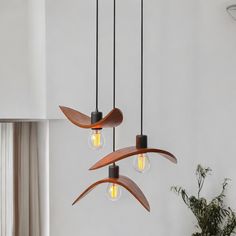 three light fixtures hanging from a ceiling in a living room with white walls and windows