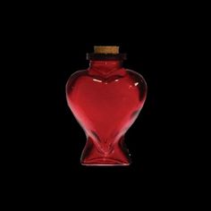 a red glass bottle with a cork in the shape of a heart on a black background