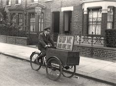 an old photo of a man on a bike with a cart attached to the back