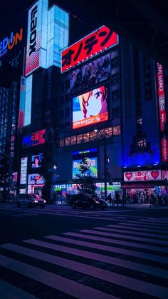 a city street at night with tall buildings and neon signs on the side of it