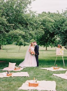 a bride and groom standing in front of an easel at their outdoor wedding ceremony