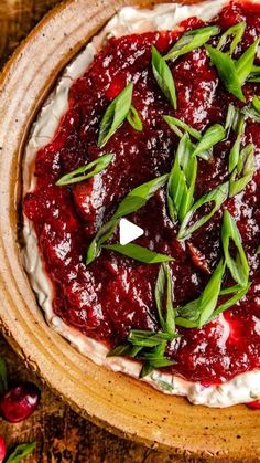 a wooden bowl filled with whipped cream and cranberry sauce on top of a table