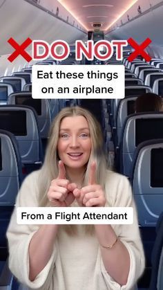 a woman is sitting on an airplane and pointing at the camera with her fingers up