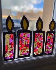 three pieces of stained glass sitting on top of a window sill