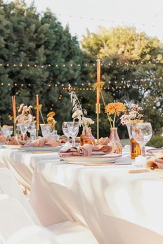 the table is set with flowers, candles and wine glasses for an outdoor wedding reception