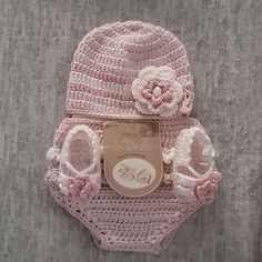 a pink hat and diaper cover are laying on a bed with the tag attached to it