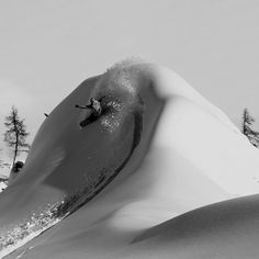 a man riding a snowboard down the side of a snow covered ski slope,