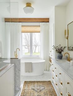 a bathroom with a tub, sink and large window