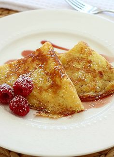 two pieces of french toast on a plate with raspberries