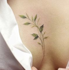 the back of a woman's shoulder with leaves on it and one green leaf