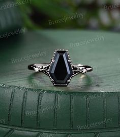 a black stone ring sitting on top of a green surface with leaves in the background