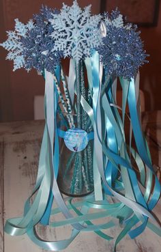 a vase filled with blue ribbon and snowflakes