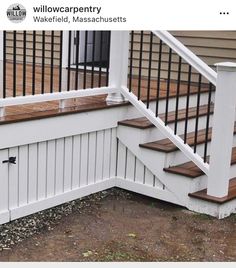 an image of a white porch with wood steps and railings on the side of a house