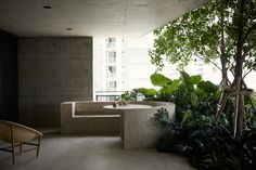 an outdoor bathtub surrounded by greenery and potted plants in a room with concrete walls