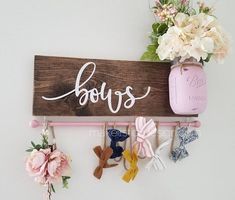 a wooden sign that says boss hangs on a wall next to flowers and baby's booties