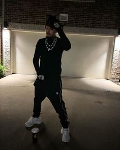 a man standing in front of a garage door with his hand on his head while wearing a hat