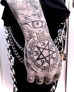 a man with tattoos on his arm and hand holding a pentagramil in front of him