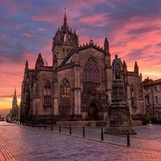 an old building with a statue in front of it at sunset or dawn, on a cobblestone street