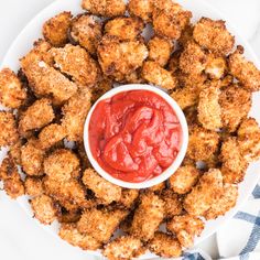 a white plate topped with tater tots covered in ketchup and sauce